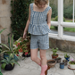 A model wearing a blue and white checkered peplum top and matching shorts. The clothing items are presented as a bundle with a save £25.