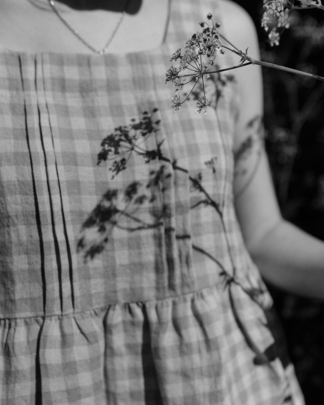 Person wearing a checkered top with floral shadows on the fabric