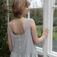 woman standing by window wearing pinafore dress with buttoned back