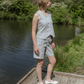 Woman in a light gray sleeveless top and shorts standing on a wooden platform by a body of water.