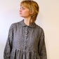 person wearing. black and natural linen check dress with a white background.