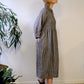 person wearing. black and natural linen check dress with a white background.