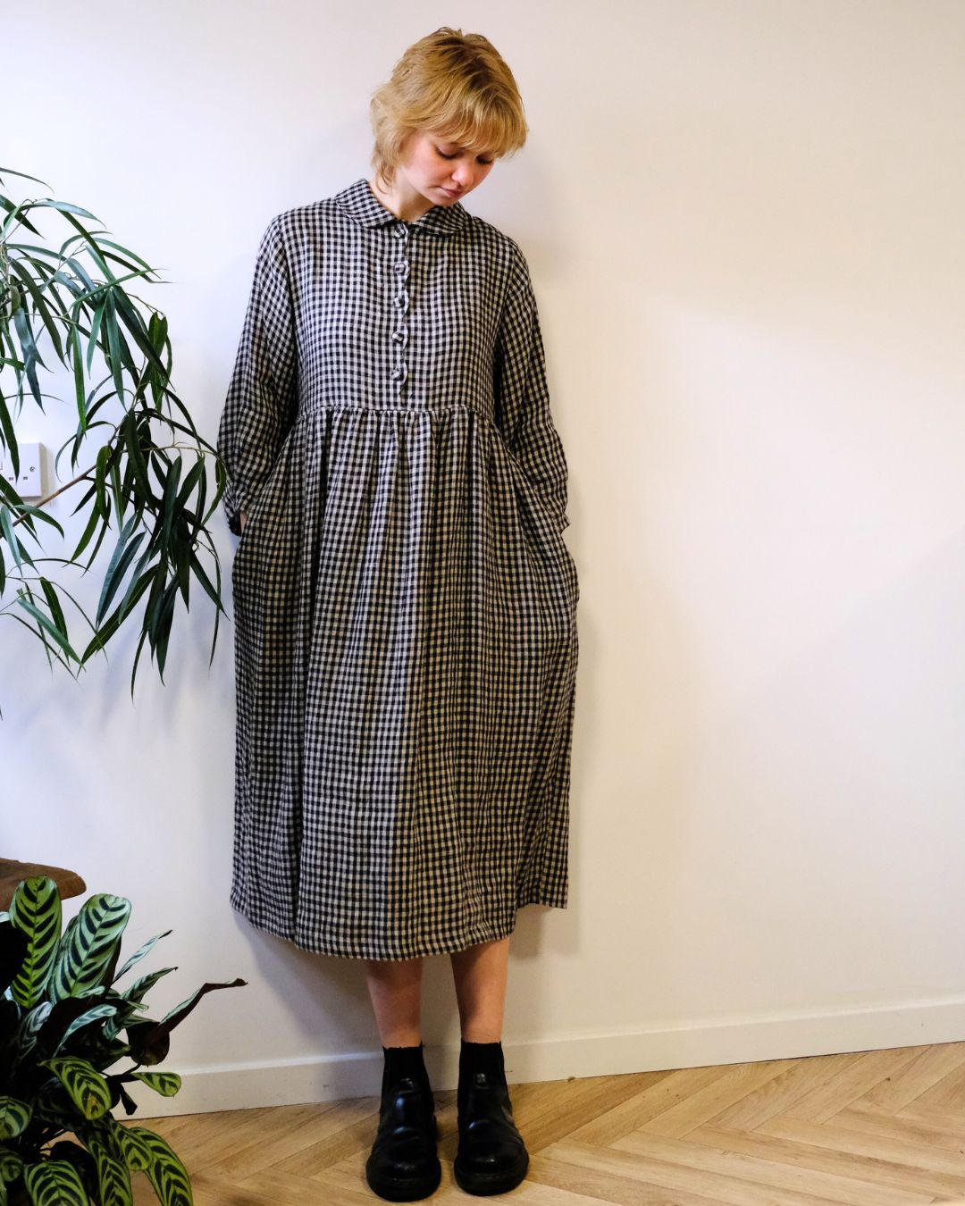 person wearing. black and natural linen check dress with a white background.