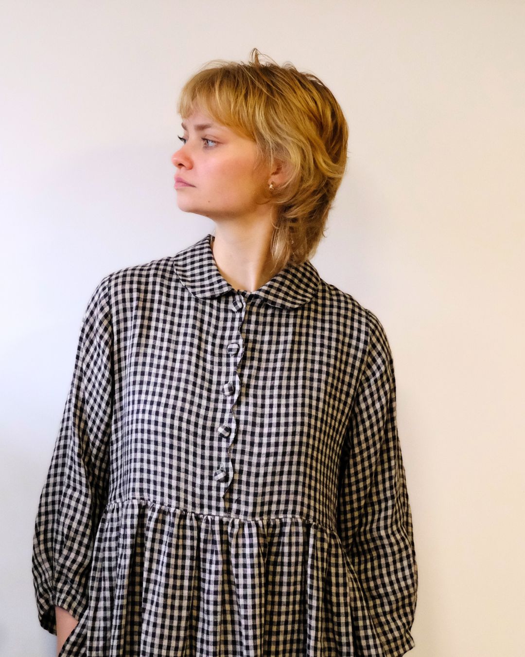 person wearing. black and natural linen check dress with a white background.