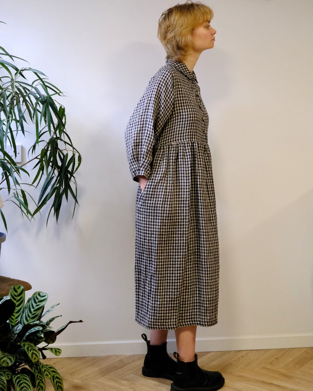 person wearing. black and natural linen check dress with a white background.