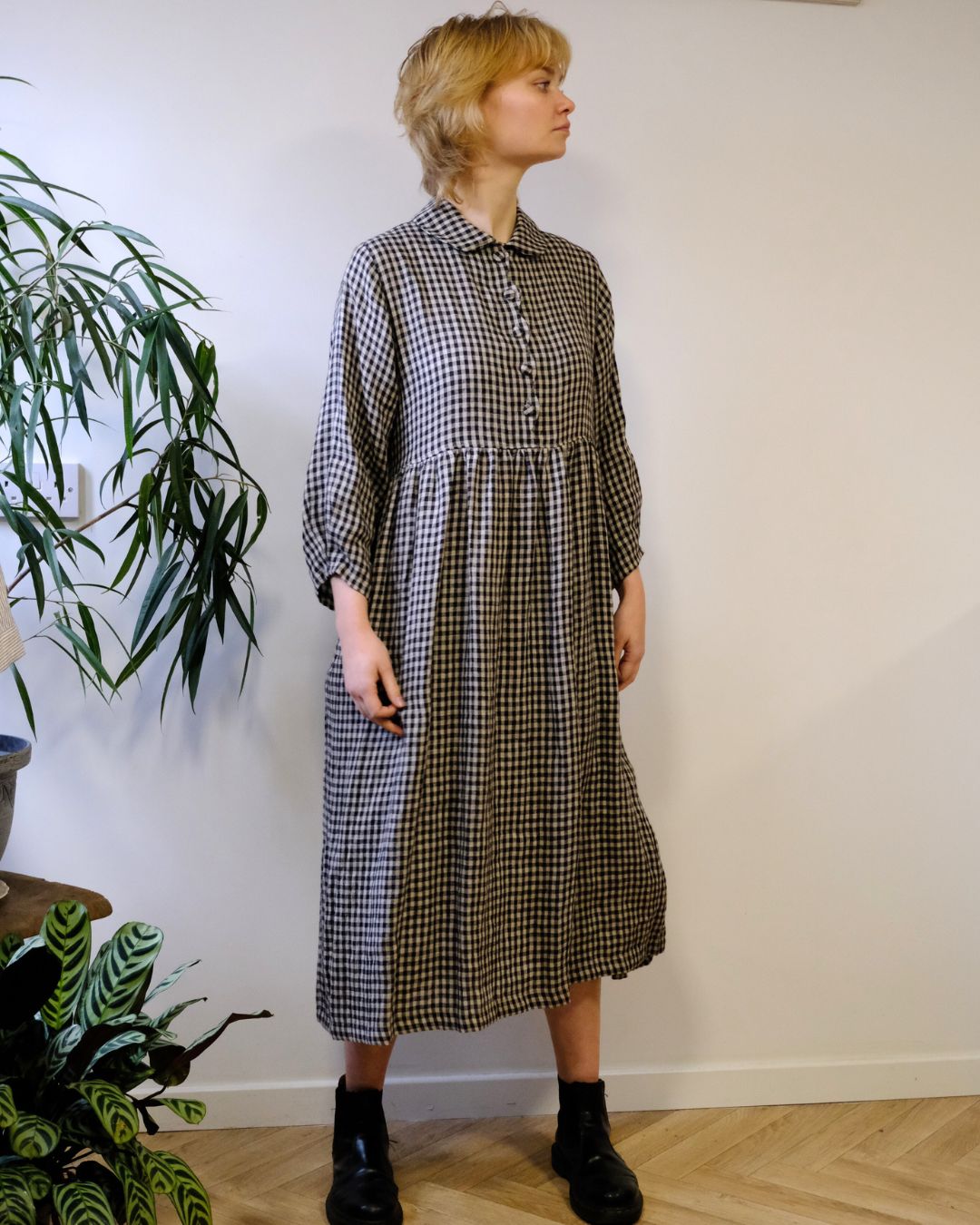 person wearing. black and natural linen check dress with a white background.