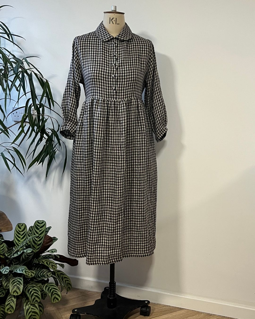 person wearing. black and natural linen check dress with a white background.