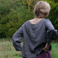 Person wearing a black and natural checkered top in a natural setting