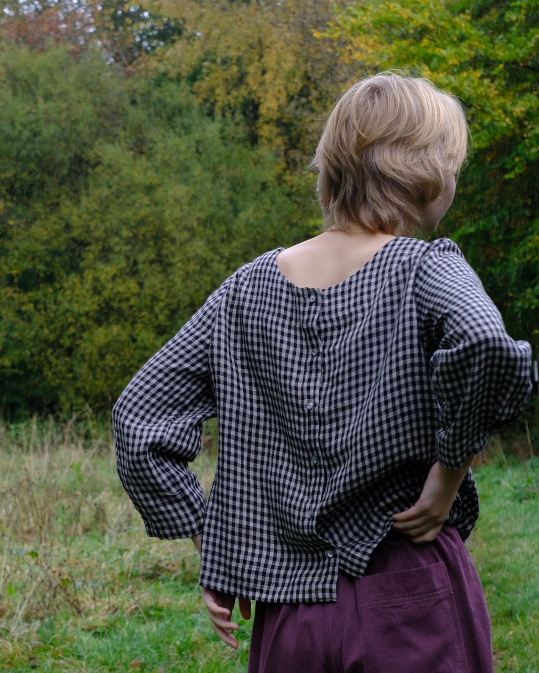 Person wearing a black and natural checkered top in a natural setting