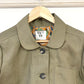 Green jacket showing  a patterned collar on a hanger against a white background