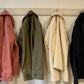 Four jackets hanging on a rack against a white wall -all different fabric options for the jacket.