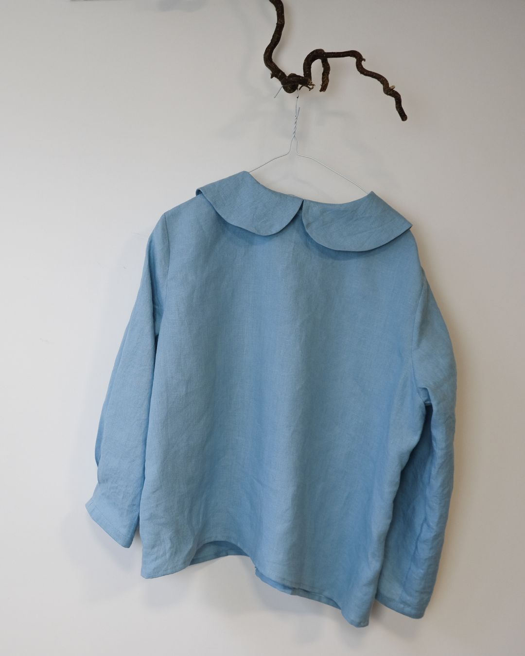 back view of blue linen shirt against white background