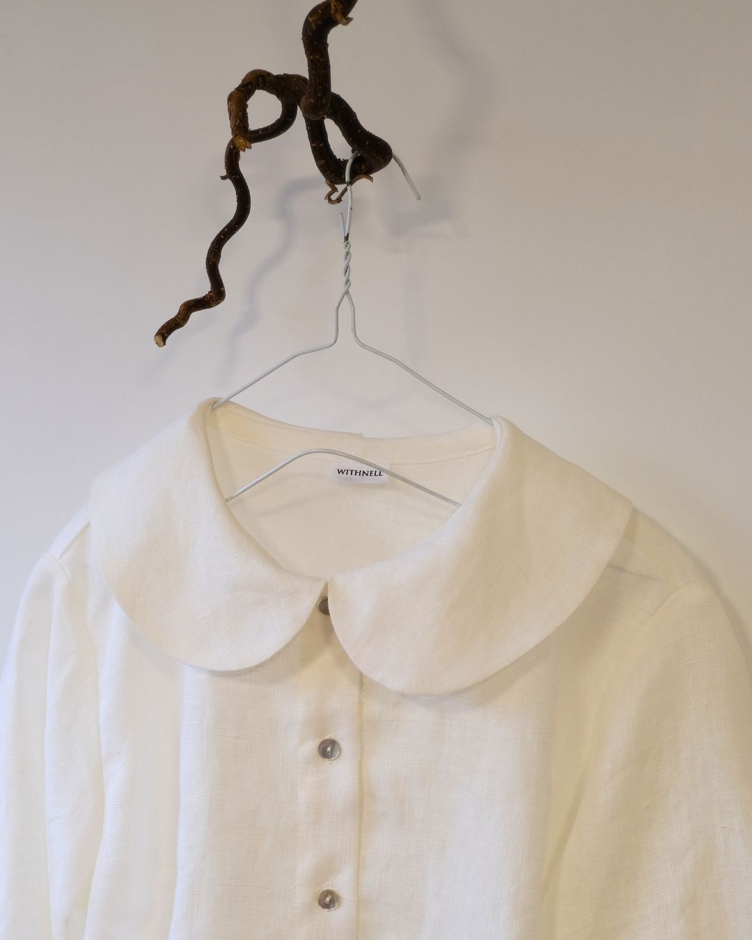 White blouse on a hanger with 'Marni' label against a plain background