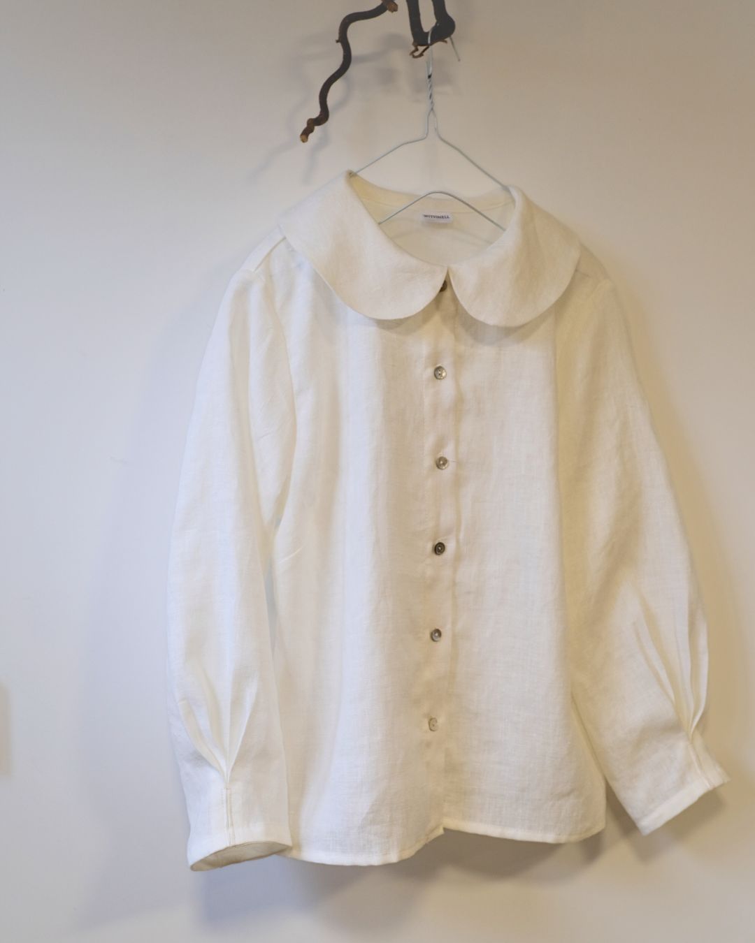 White shirt with a collar on a hanger against a white background