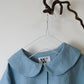 blue  linen shirt with peter pan collar and 6 buttons hanging from a twig against a white background