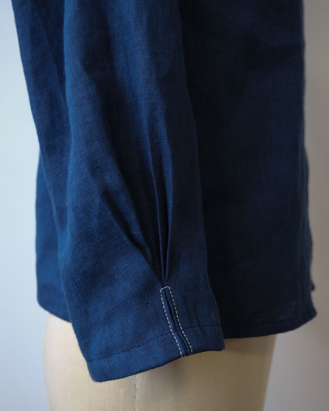 Close-up of a blue denim shirt on a mannequin with a neutral background