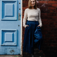 Woman standing by the side of a blue door wearing stripe top and blue culottes