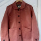 pink jacket on a wooden hanger against white background.