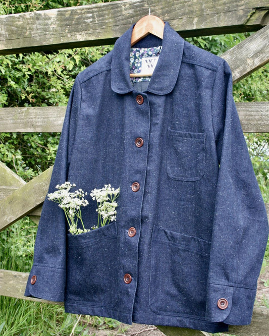 denim jacket  with flowers in front pocket hanging from a field gate.