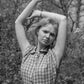 Black and white photo of a woman in a checkered dress posing outdoors.