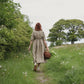 Woman walking in country setting wearing  beige linen dress